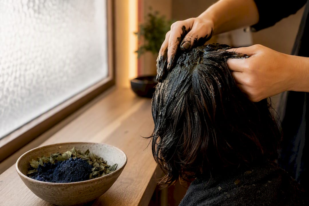 Mani che applicano pasta naturale di henné nero sui capelli